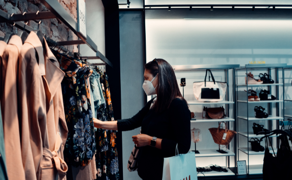 A person shops in a clothes store wearing a face mask